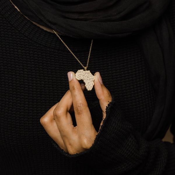 A model wearing the gold-plated Ayatul Kursi Country Map Necklace, with the pendant resting elegantly on her chest, highlighting the intricate design.