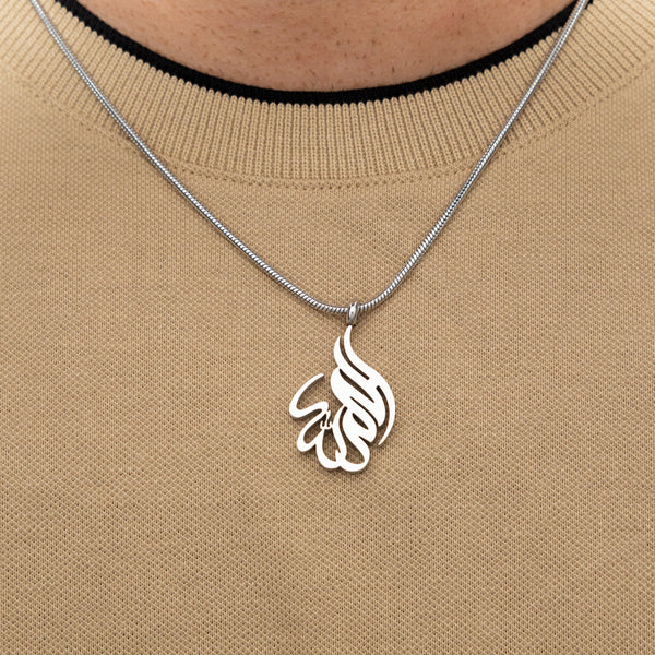 Silver 'Alhamdulillah' calligraphy necklace worn over a beige knit top.
