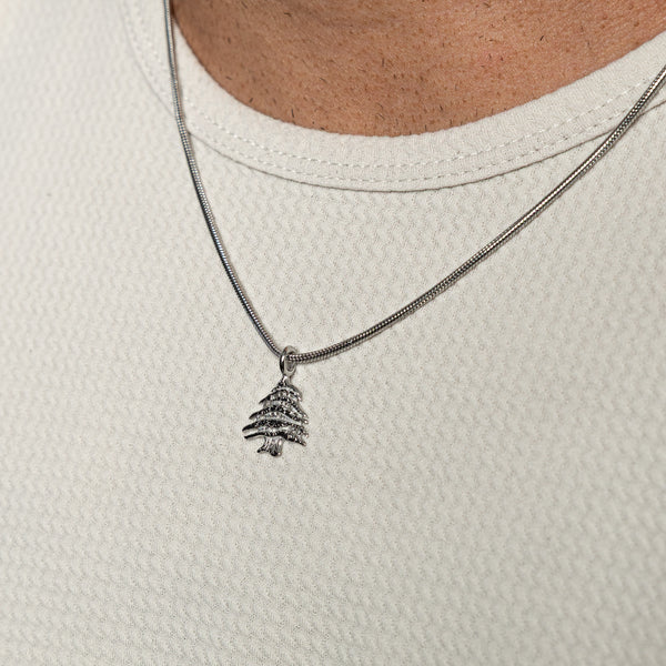 Silver Cedar of Lebanon necklace worn over a textured white shirt.