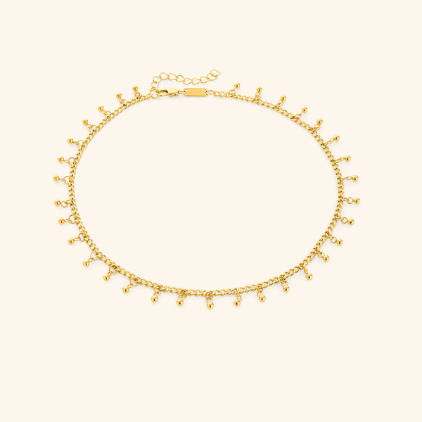 A close-up of the Dangling Dotted Choker in 18K gold plating. The choker features a delicate chain with evenly spaced 3mm spherical bead accents that dangle, creating a subtle and elegant design.
