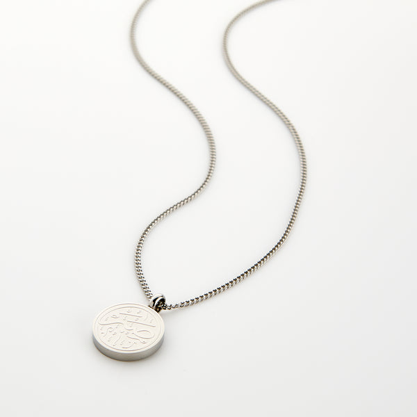 Silver necklace with a circular 'Sabr' calligraphy engraved pendant, displayed on a white background.