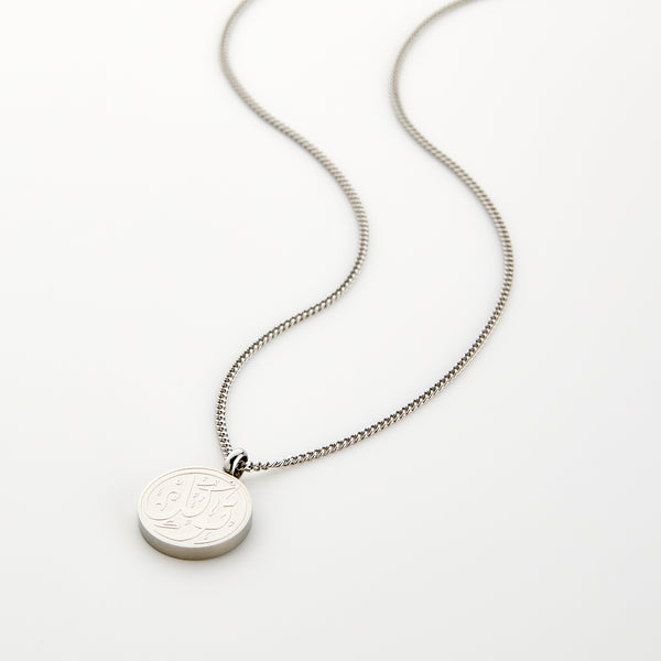 Silver necklace with a circular pendant engraved with 'Tawakkul' calligraphy, displayed on a white background.