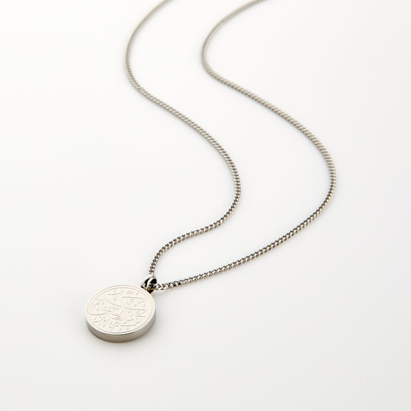 Silver necklace with a circular pendant engraved with 'Maktub' calligraphy, displayed on a white background.