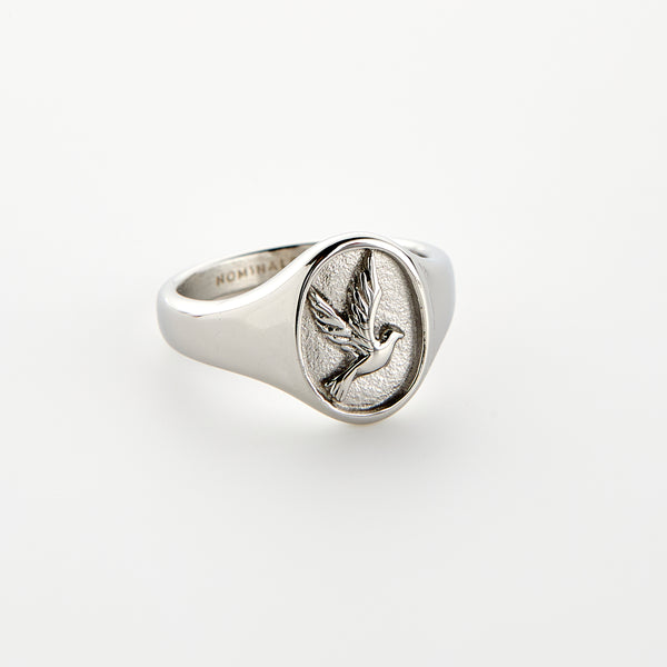 A silver ring of tranquility featuring a raised dove design, set against a white background.