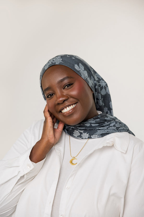 A model wearing the Damask Rose Crescent Necklace at its full 22-inch length. The necklace rests gracefully on the collarbone, highlighting the crescent moon pendant with rose detailing against a simple, neutral-toned outfit.