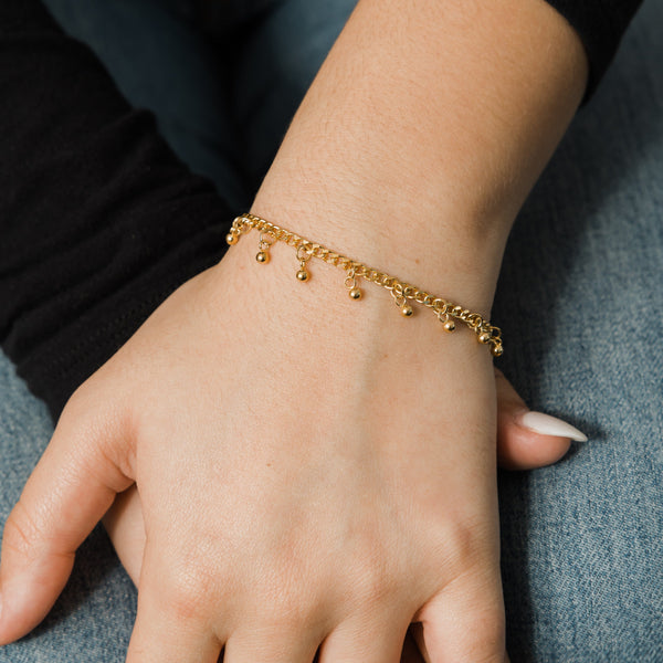 A close-up of the "Dangling Dotted Bracelet" by Nominal, showcasing its intricate design with multiple small charms that dangle and move. The bracelet has a classic, everyday-wear style.