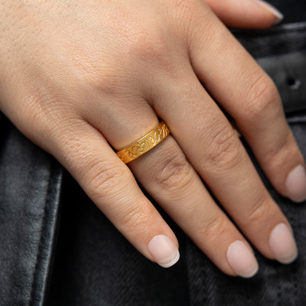Woman wearing the gold Rahma Mercy Ring on her ring finger, arabic calligraphy clearly visible.