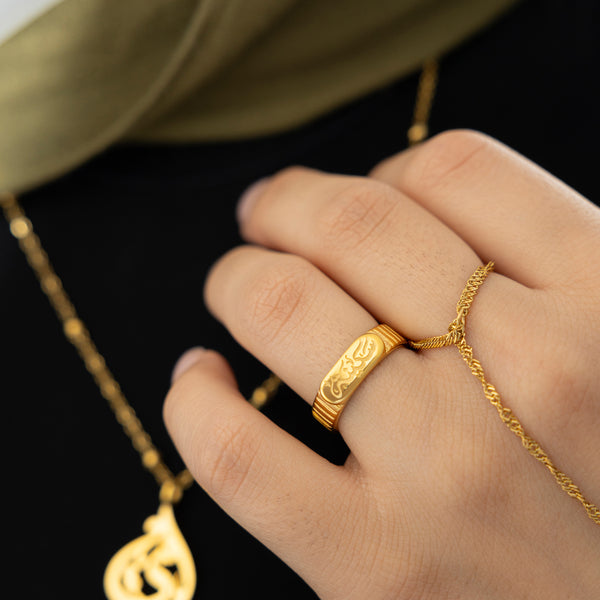 Gold Sakinah serenity ring styled with a gold twisted hand chain, worn on the ring finger, paired with a gold necklace.