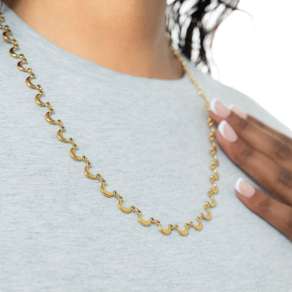 A model wearing the 18K gold-plated Skyfall Necklace. The crescent charms rest delicately along her collarbone, complementing her minimalist attire.