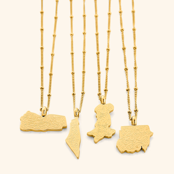 Four gold "With Hardship Comes Ease" Map Necklaces displayed side by side on a white background, each featuring a unique map-shaped pendant engraved with Arabic calligraphy, highlighting variations in map designs and delicate gold chains.