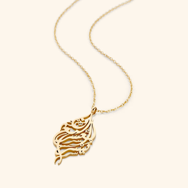 A close-up of the "Verily, With Hardship Comes Ease" Calligraphy Necklace in 18K gold plating. The pendant features the Arabic inscription "إِنَّ مَعَ الْعُسْرِ يُسْرًا" ("Verily, with hardship comes ease") in elegant calligraphy, suspended from a delicate gold chain.
