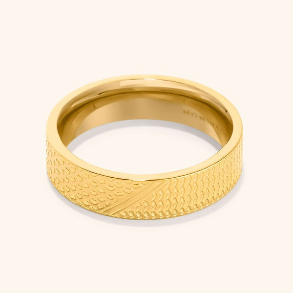 A close-up of the Keffiyeh Ring in 18K gold plating, featuring intricate engravings inspired by the traditional Palestinian keffiyeh pattern, including fishnet designs symbolizing the sea, bold lines representing trade routes, and olive leaves honoring cultural heritage. The ring has a polished finish and is displayed against a neutral background.