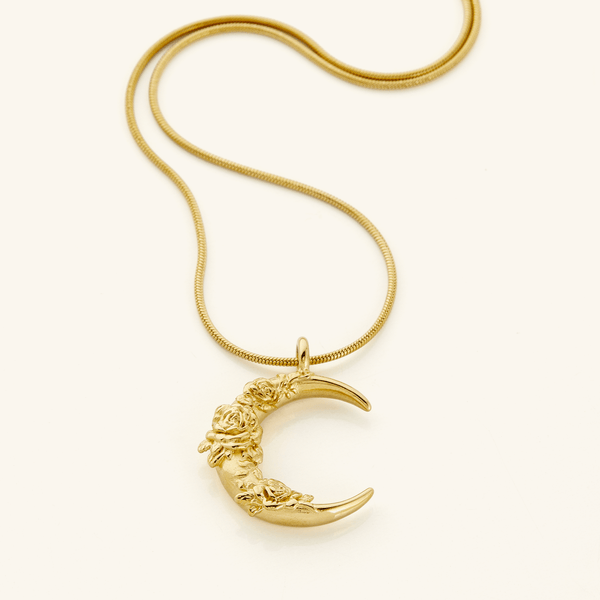 A close-up of the Damask Rose Crescent Necklace in 18K gold plating. The pendant features a crescent moon adorned with intricate damask rose detailing, suspended from a delicate gold chain.