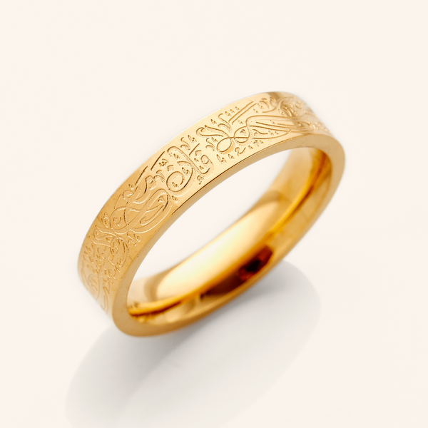 A gold ring with an intricate design etched around the outer surface. The design appears to be Arabic script. The ring is displayed on a bright white background with a soft shadow underneath. Given the design and the product name "With Hardship Comes Ease" Ring, it's plausible that the inscription holds religious or inspirational significance, potentially related to Islamic teachings.
